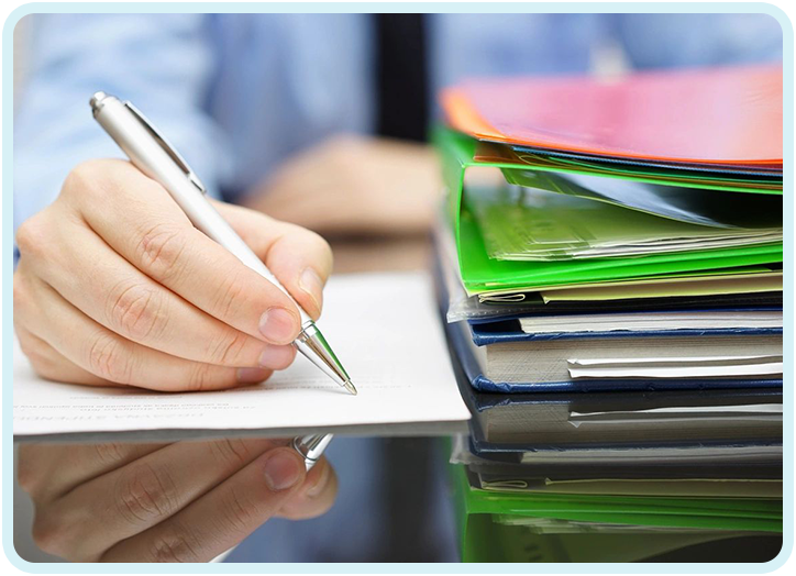 A person writing on paper next to some books