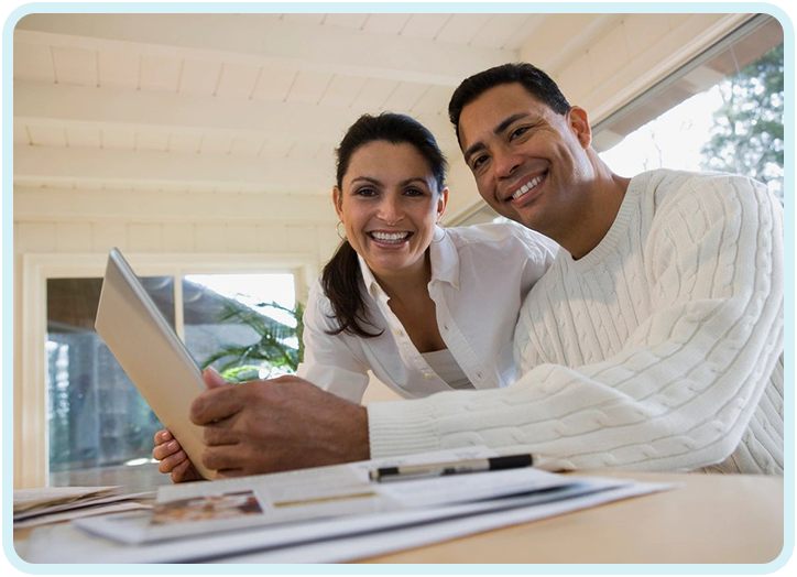 A man and woman smile while looking at an ipad.